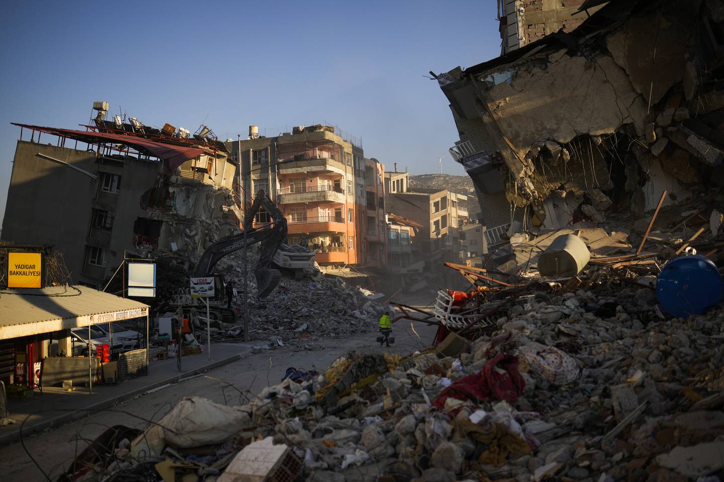 A man carries buckets as he walks among destroyed buildings after the earthquake in Samandag, southern Turkey, Thursday, Feb. 16, 2023. The number of people killed in the Feb. 6 earthquakes that devastated parts of southern Turkey and northern Syria continues to rise. As chances of finding more survivors dwindled, some foreign search teams that rushed in to help have started leaving.