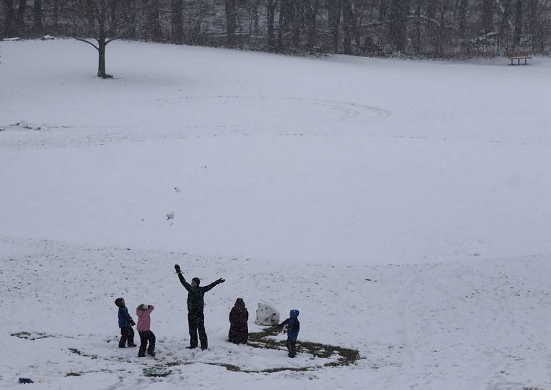 Members of the Anderson family of Crystal Lake toss snow into the air as they build a snowman in Veterans Acres Park as a winter storm moves through McHenry County on Tuesday, Jan. 9, 2024, delivering snow to most of the county.