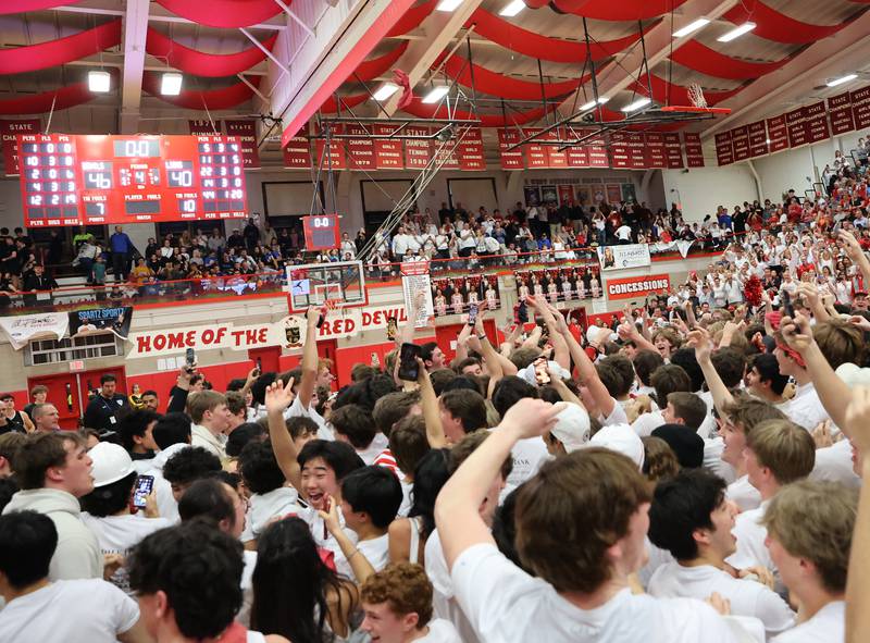 Hinsdale Central fans storm the court after a 46-40 victory at the boys 4A varsity sectional semi-final game between Hinsdale Central and Lyons Township high schools in Hinsdale on Wednesday, March 1, 2023.