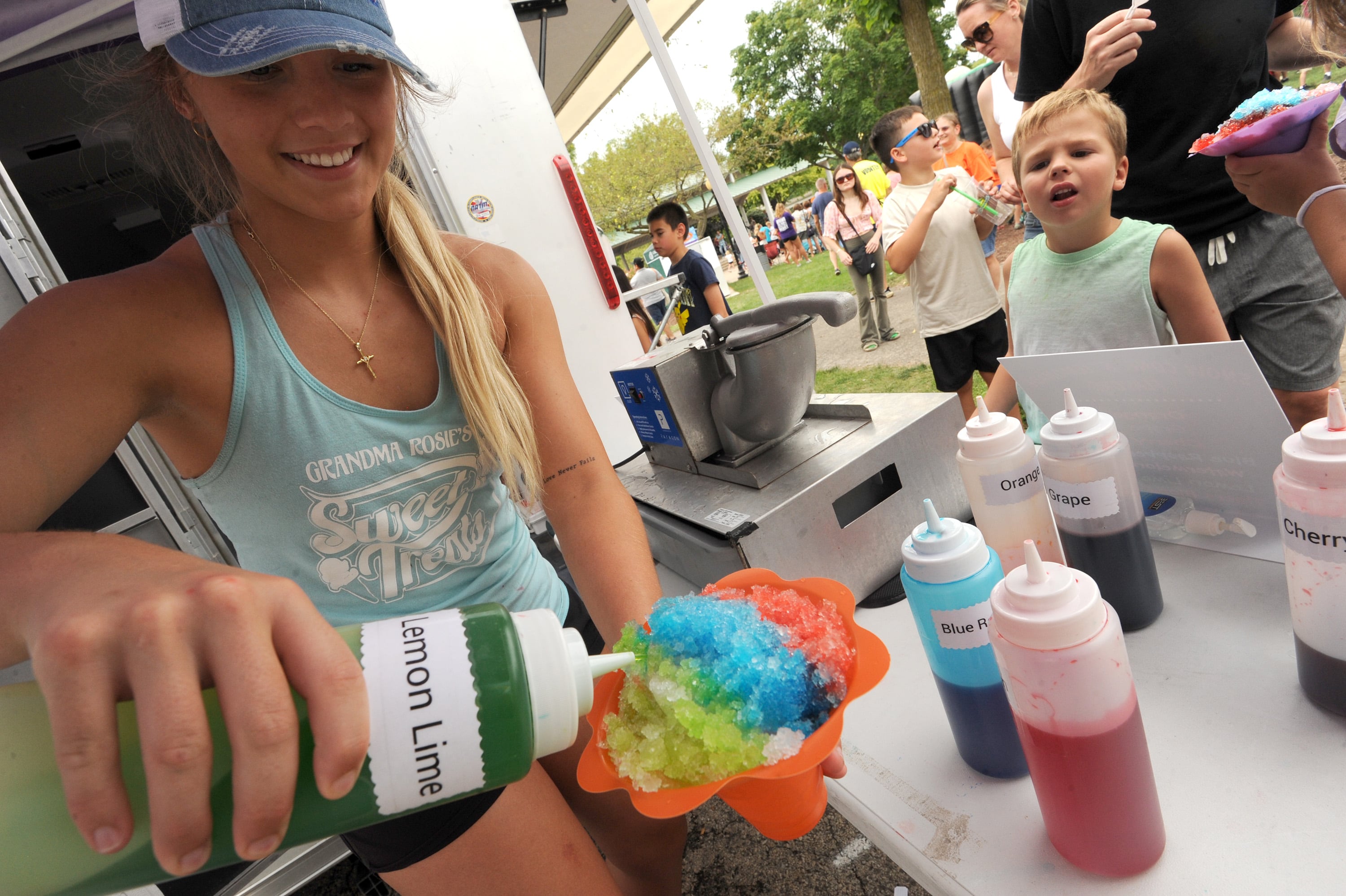 Chloe Saxe prepares a colorful Snow Cone at the Grandma Rosie's Sweet Treats during Riverfest on Hydraulic Avenue in Yorkville on Saturday, July 20, 2024.