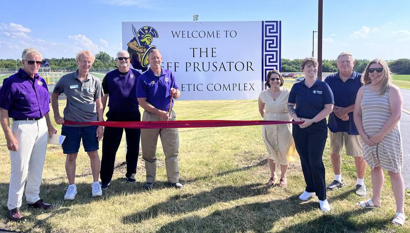 Former Mendota superintendent Jeff Prusator (fourth from left) cuts the ribbon on the new sign at the Jeff Prusator Athletic Complex on Monday, June 17, 2024 at Mendota High School. He was joined by (from left) Mendota board president Jim Lauer, Mendota Chamber of Commerce ambassador Lee Stocking, Mendota principal Joe Masini, Mendota superintendent Denise Aughenbaugh, Chamber president and CEO Sam Setchell and Mendota board members Jim Strouss and Sarah Coss.