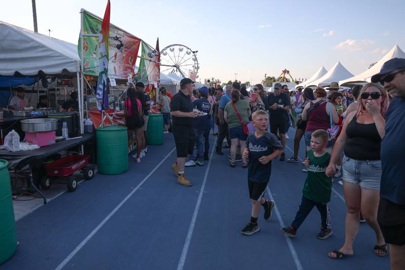 People wait in line at one of the dozens of food tents at the Taste of Joliet on Friday, June 21, 2024 at Joliet Memorial Stadium.