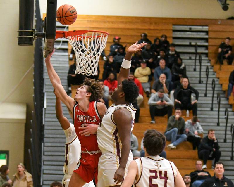 Yorkville's Bryce Salek, center makes a basket while being defended by St. Ignatius's Justin Scott, right, and fouled by St. Ignatius's Reggie Ray (25) in the second quarter on Tuesday Dec. 26, 2023, during the Jack Tosh tournament held at York High School in Elmhurst.