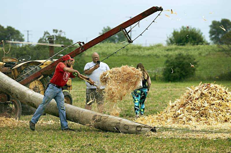 Adam Betz of Compton tosses debris from a corn shucker  Saturday, August 5, 2023 at the Living History Antique Equipment Association’s farm show in Franklin Grove.