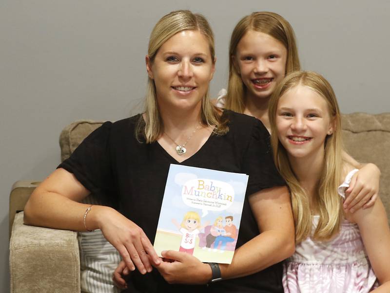 Stacy Salomone Whitcomb holds her new children’s book, “Baby Munchkin” next to her children, Reese, 9, and Hayden, 11, whom the book is based, at their hame in Cary on Friday, June 28, 2024.