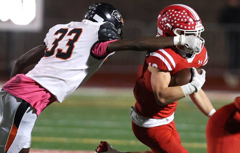 DeKalb’s Jauharie Wilson grabs the facemask of Naperville Central's Aiden Clark during their game Friday, Oct. 6, 2023, at Naperville Central High School.