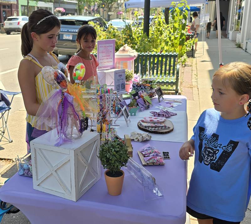 A customer visits Ana Elisa (left) and Thaila Scheick's business Star Designs on Saturday, Aug. 24, 2024, during the third annual Prairie Fox Books Children's Business Fair in downtown Ottawa.