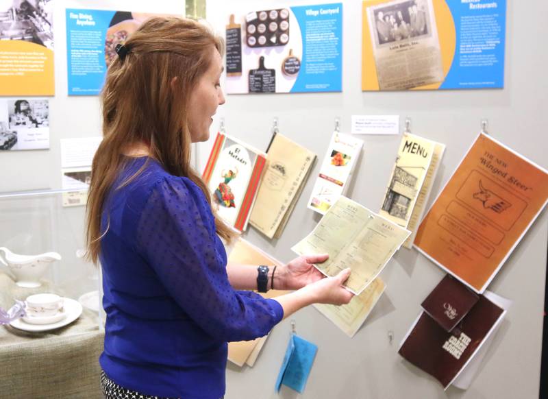 Michelle Donahoe, executive director of the DeKalb County History Center, looks at food menus from the past Thursday, June 6, 2024, in the new exhibit “Food: Gathering Around the Table,” now open at the center in Sycamore. The exhibit was created by the DeKalb County History Center in collaboration with the Smithsonian Institution's Museum on Main Street program.