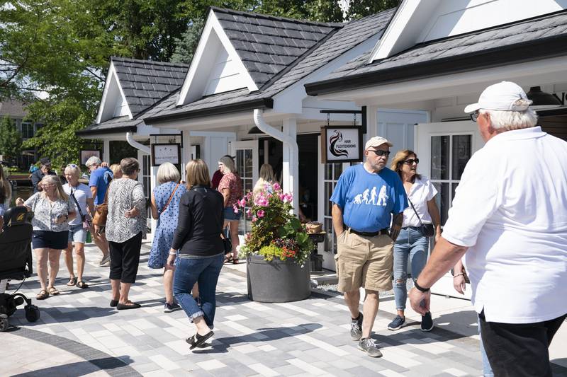 Shoppers explore the new collection of tiny shops at the grand opening and ribbon cutting of the new McHenry Riverwalk Shoppes in downtown McHenry on Friday, July 21, 2023.