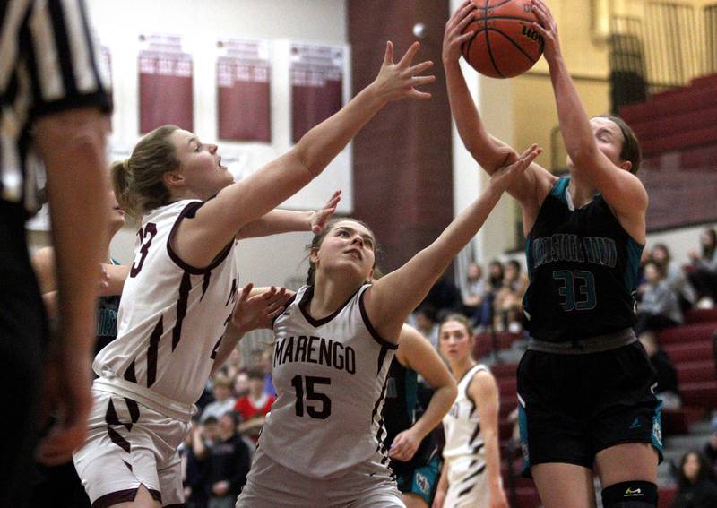 Marengo’s Madison Cannon, left, and Emilie Polizzi, center, battle Woodstock North’s Adelynn Saunders, right, in varsity girls basketball at Marengo Tuesday evening.