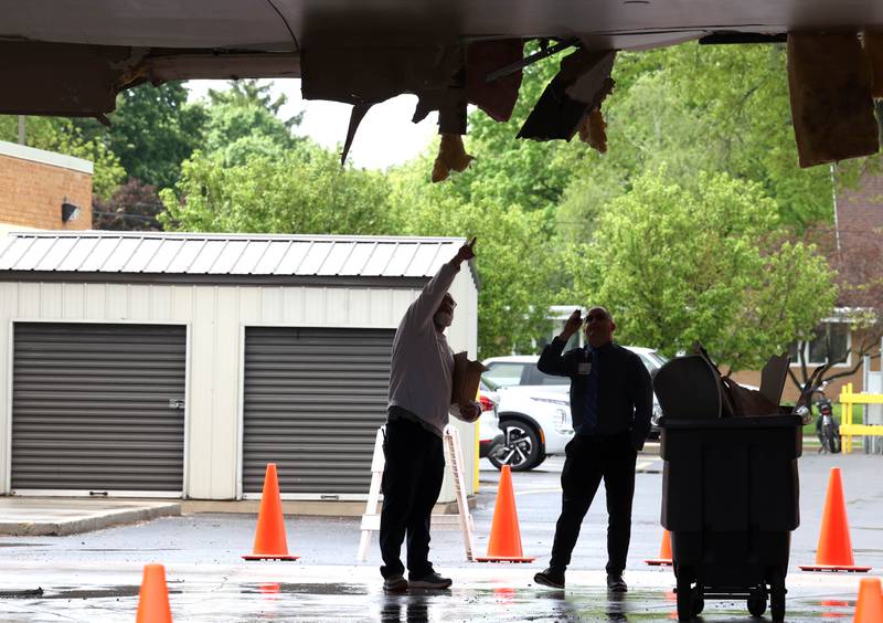 Northwestern Medicine Valley West Hospital employees inspect the damage in the ambulance bay after a truck too tall for the clearance tried to drive through it Tuesday, May 7, 2024, at the hospital in Sandwich. There was visible damage to the ceiling of the bay with insulation a wall material hanging down.