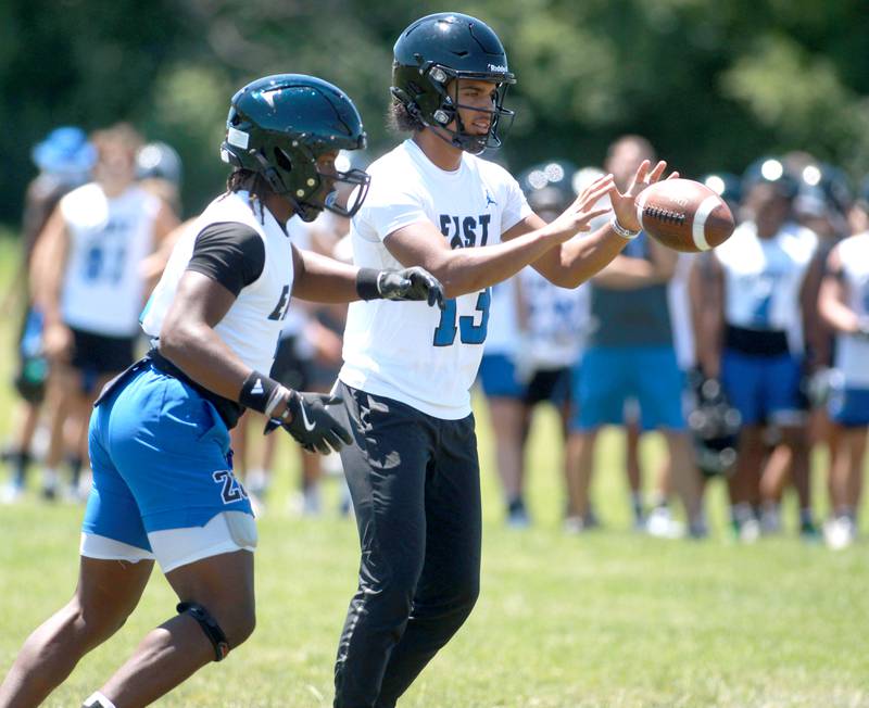 Lincoln-Way East quarterback Jonas Williams (right) gets the snap during a 7-on-7 tournament at Naperville North on Thursday, June 27, 2024.