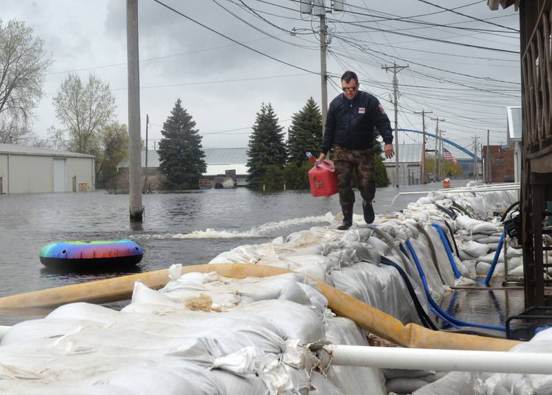Jacob Helms, a volunteer Savanna firefighter, walks on top of the sandbag wall as he refuels pumps just west of Main Street. Firefighters along with volunteers and inmates from Kewanee and East Moline, constructed the wall with 46,000 sand bags in anticipation of river levels rising past the 21-foot mark.
