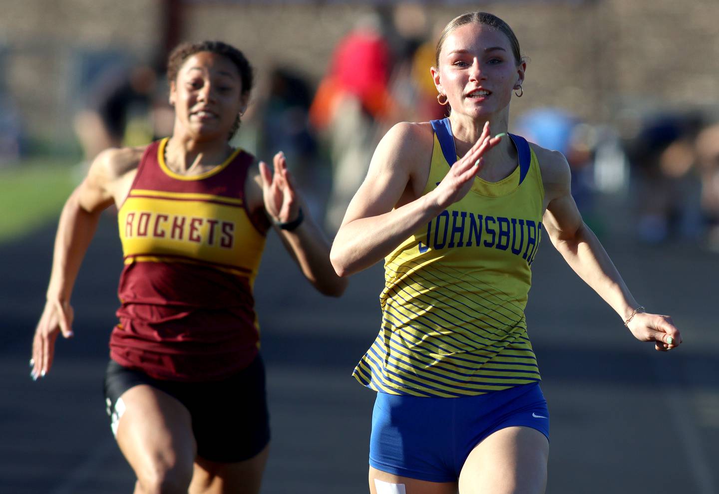 Johnsburg’s Caitlyn Casella, right, cruises to victory in the 100-meter dash as Richmond-Burton’s Jasmine McCaskel pursues during the Kishwaukee River Conference Girls Conference Championships track meet at Harvard High School Tuesday.