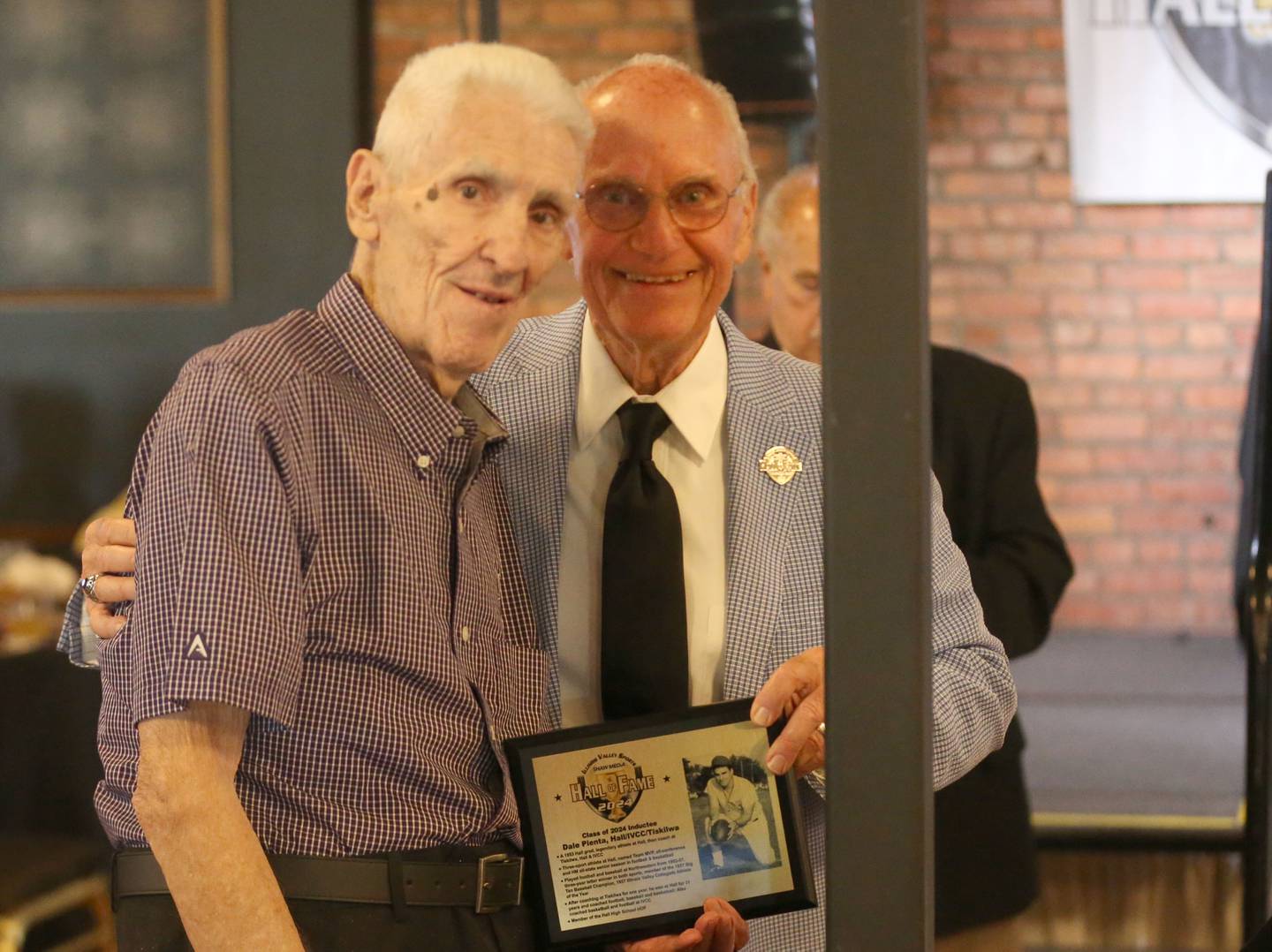 Dale Pienta, a Hall High School graduate, Tiskilwa track coach and Illinois Valley Community College basketball coach poses with his award with emcee Lanny Slevin during the Illinois Valley Sports Hall of Fame awards banquet on Thursday, June 6, 2024 at the Auditorium Ballroom in La Salle.