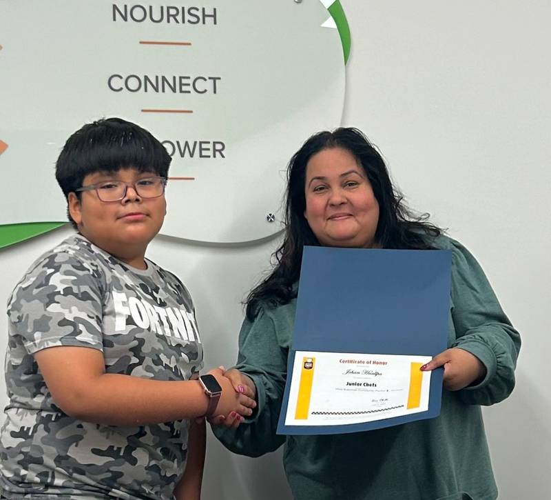 Johan Hualpa was one of several graduates who received a certificate from Support Services Coordinator Nancy Chatterjee, as well as a cookbook and the ability to prepare healthy snacks and meals for themselves and their families.