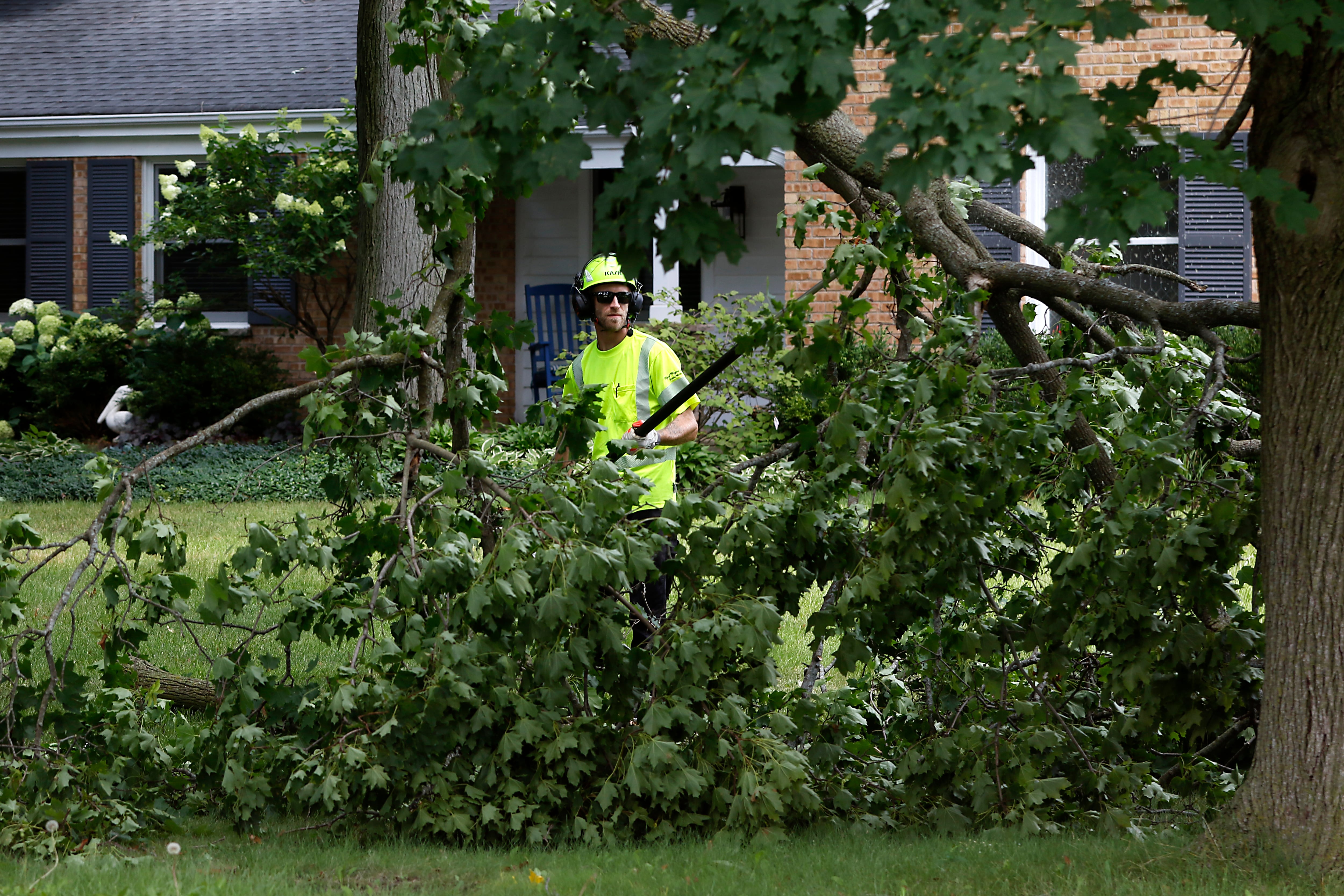 A worker for the Crystal Lake Department of Public Works remove storm debris near the intersection of Golf Road and Highland Avenue on Tuesday, July 16, 2024, after McHenry County was hit by its third night of severe thunderstorms,