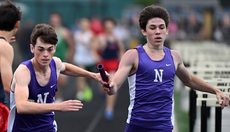 Downers Grove North’s Ryan Eddington, left, takes the baton from Grant Schroder in the 3,200-meter relay during the Class 3A Glenbard North boys track and field sectional on Thursday, May 16, 2024 in Carol Stream.