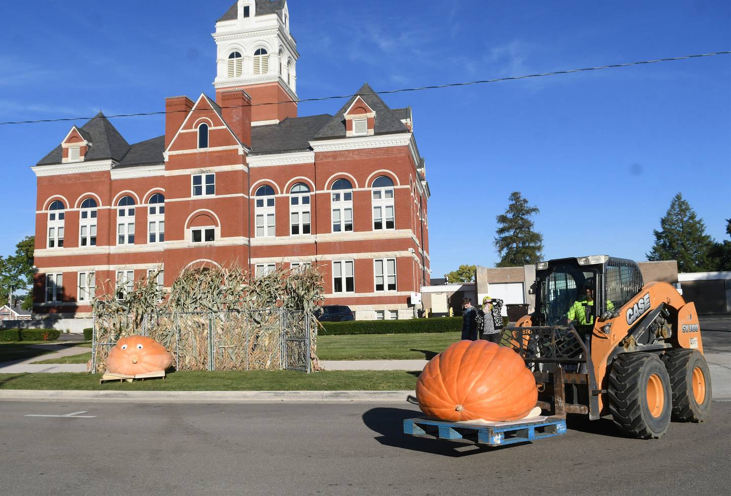 Jeremy Benesh of Benesh & Sons uses a skidsteer to move Tank one of Theresa Miller's giant pumpkins next to the 1,032-pound Twaddle B2 on N. Fifth Street for this weekend's Autumn on Parade festival.