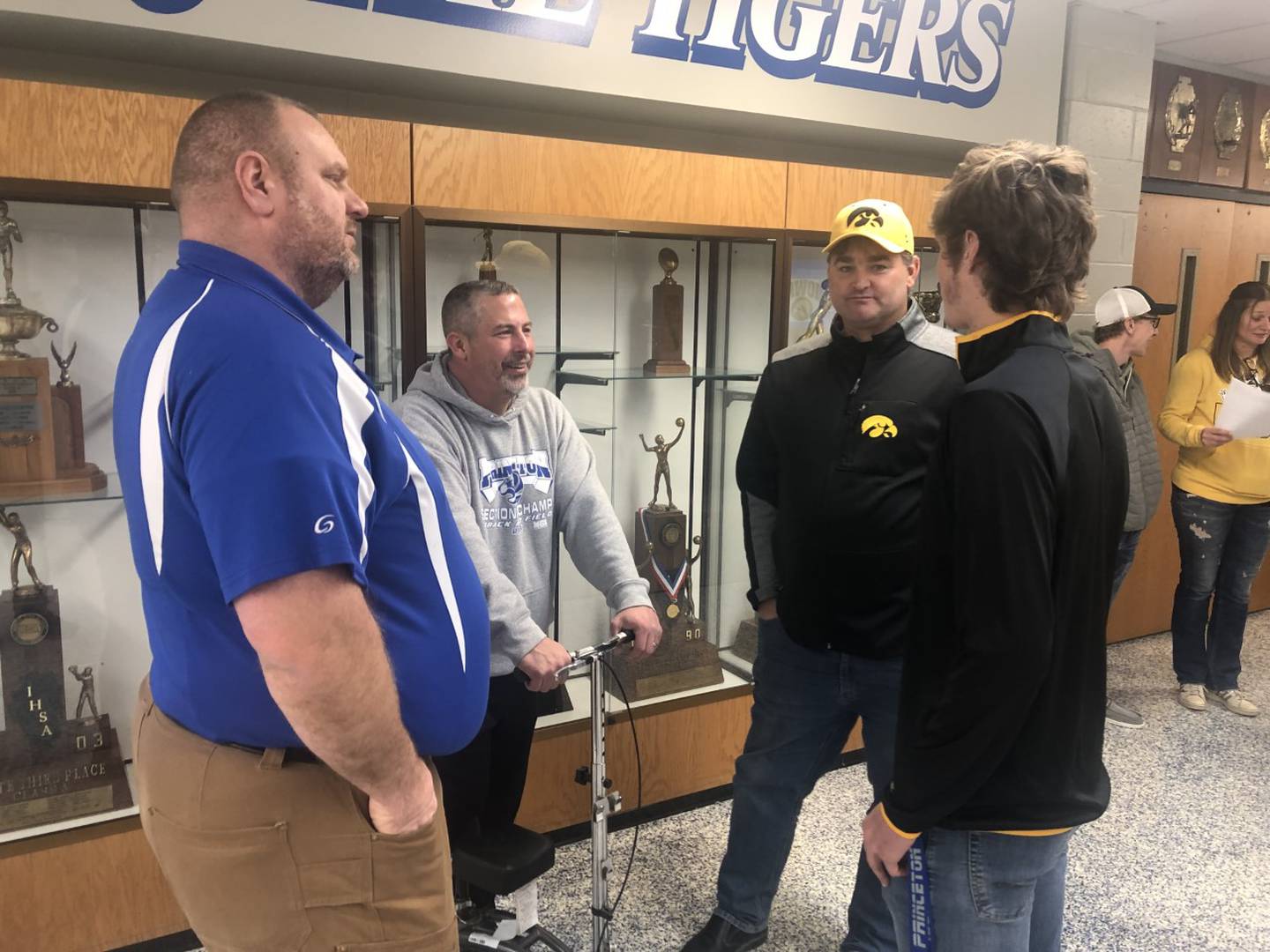 Princeton High School track coaches Dan Foes (from left) and Rob Jensen chat with PHS senior Teegan Davis and his father, Spencer, after signing his National Letter of Intent to play football for the University of Iowa.