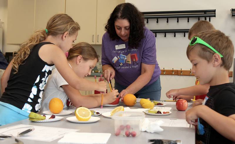 Youth Services Manager Gina Knowlton helps kids with an experiment at the Town and Country Library on Friday, June 21, 2024 in Elburn.