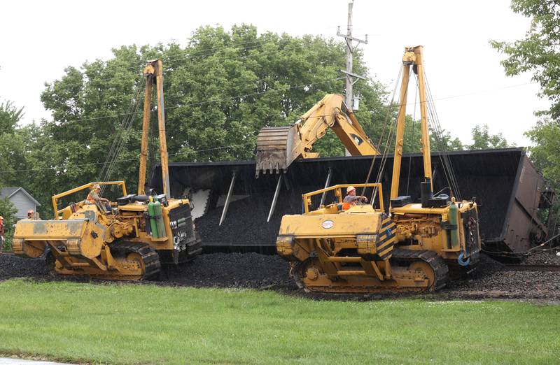 Cranes and a loader get into position to upright a tipped over coal car after a BNSF Railway train traveling east derailed Wednesday, July 10, 2024, near Route 34 on the west side of Somonauk.