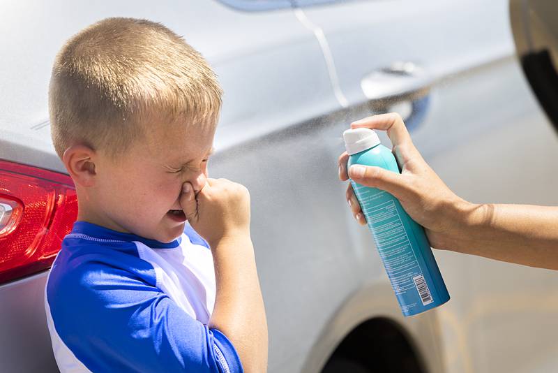 Carson Worley, 5, plugs his nose while getting a spritz of sunscreen Wednesday, June 12, 2024 by babysitter Madison Duhon. The two were about to cool off at the Dixon Park District splash pad.