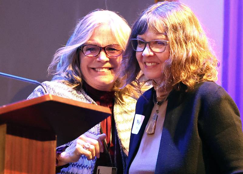 Women of Accomplishment Honoree Nancy Proesel (right) is welcomed to the stage Thursday, Oct. 19, 2023, during the Athena and Women of Accomplishment Awards reception hosted by the DeKalb Chamber of Commerce at the Egyptian Theatre.