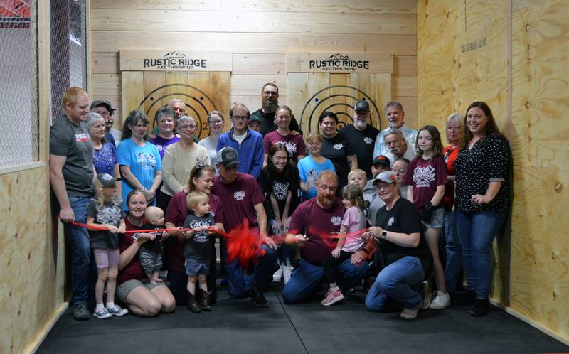 Chris Chapman holds daughter Evalynn, 5, as he cuts a ribbon during the grand opening of Rustic Ridge Axe Throwing on May 28 in Oregon. Chapman is the manager; his wife, Cassandra Chapman (to his right) is the owner. Rustic Ridge Axe Throwing is located at 117 N. 4th St., Oregon, and is affiliated with the World Axe Throwing League.