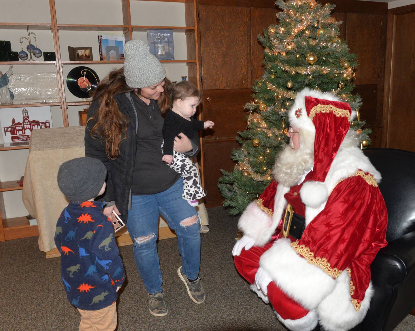 The Schopp family of Oregon visited with Santa Claus during Oregon's Candlelight Walk on Saturday, Nov. 25. 2023. Here, Carson, 3, and his sister Kelsey, 11 months, and their mom, Kelsey, visit with Santa. The event also included Christmas music, shopping specials, and visits with Santa.