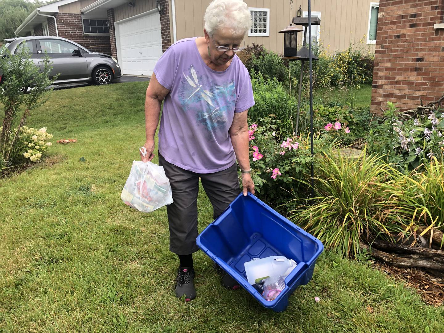 Jean Hervert Niemann of Woodstock holds a garbage bag and her recycling bin Aug. 15, 2024.