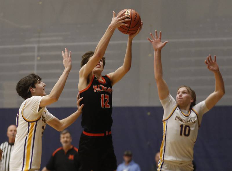 McHenry's Caleb Jett drives to the basket between Hononegah's Brayden Olson (left)  and Cole Warren (right)during the IHSA Class 4A Guilford Boys Basketball Sectional semifinal game on Wednesday, Feb. 28, 2024, at Rock Valley College in Rockford.