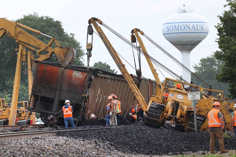 Cranes and a loader upright a tipped over coal car after a BNSF Railway train traveling east derailed Wednesday, July 10, 2024, near Route 34 on the west side of Somonauk.