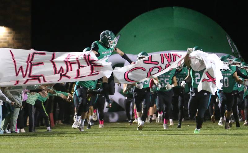 Seneca's Paxton Giertz breaks the banner as the Irish take the field against Marquette on Friday, Oct. 18, 2024 at Seneca High School.