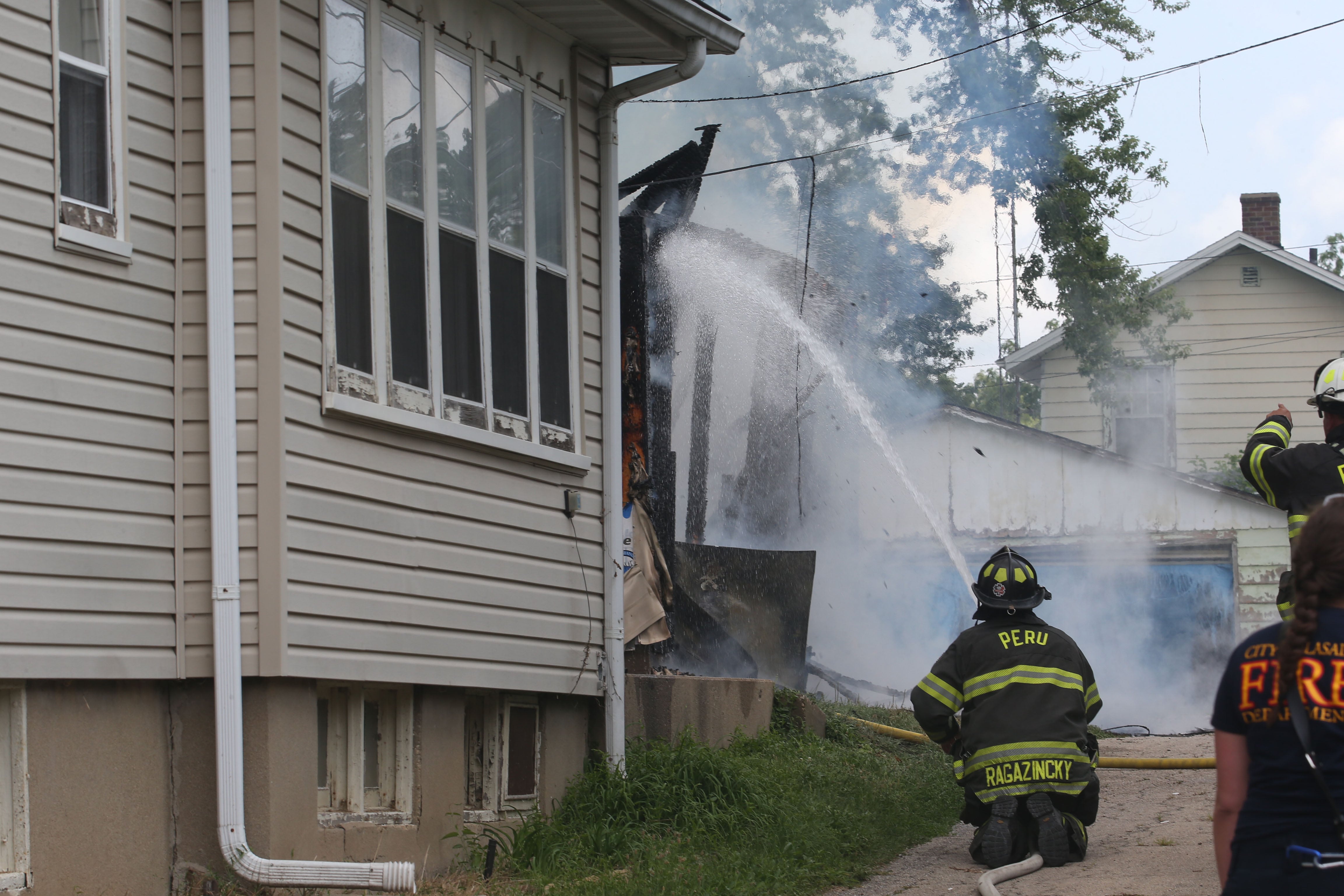 Peru firefighter Pete Ragazinski extinguishes flames from a garage fire in the 800 block of Lafayette Street on Monday, July 22, 2024. The fire began just before 1p.m. La Salle Fire and EMS along with Peru Fire department responded to the call while La Salle Police directed traffic.