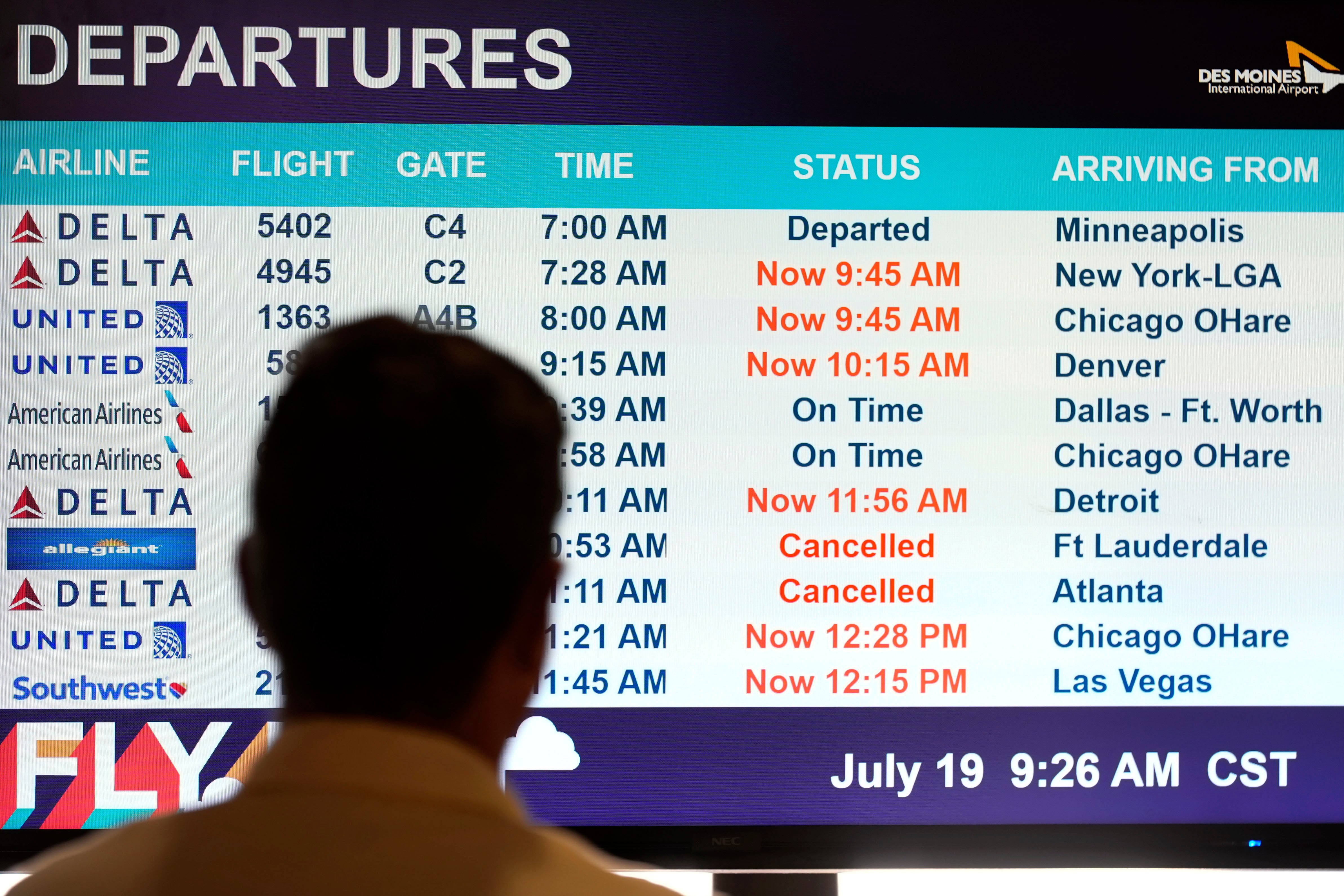 A passenger looks at a departures monitor at the Des Moines International Airport, Friday, July 19, 2024, in Des Moines, Iowa. (AP Photo/Charlie Neibergall)