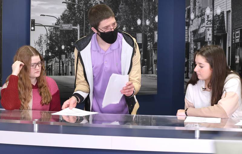 Educator Gregory D'Addario, who teaches TV production and english at Sycamore High School, goes through some script revisions with sophomore anchors Kennedy McCoy, (left) and Hailey Clawson before they tape a news program Wednesday, March 1, 2023, at the school.