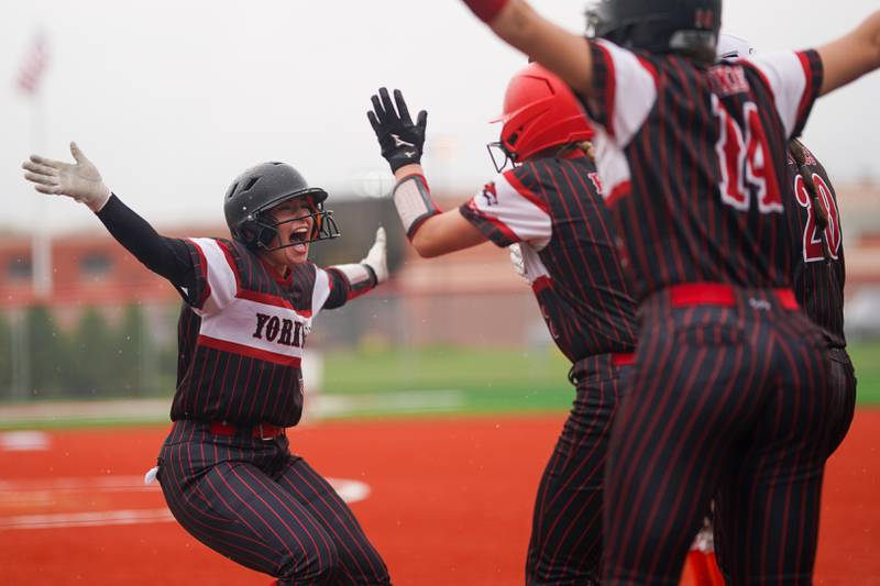 Yorkville's Regan Bishop (left) reacts after crossing the plate to score a run against Oswego during a softball game at Yorkville High School on Thursday, May 9, 2024.