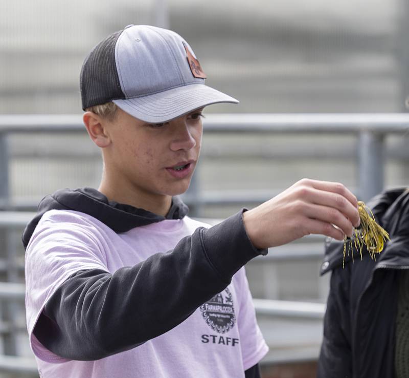 FFA member Denver Sandrock talks about a lure Thursday, May 9, 2024, at the fishing booth at Farmapalooza.