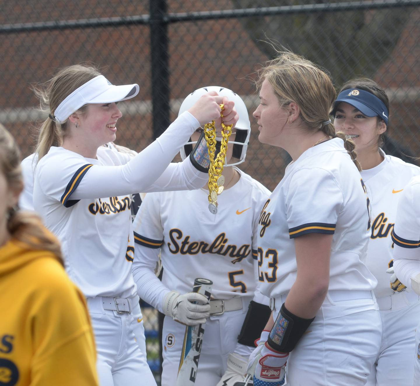 Sterling's Olivia Melcher (left) gets ready to put the golden necklace on Sienna Stingley after she hit a home run against Erie-Prophetstown during a Saturday, March 16, 2024 game at Sterling High School. Stingley was one three Warriors who hit home runs in the inning.