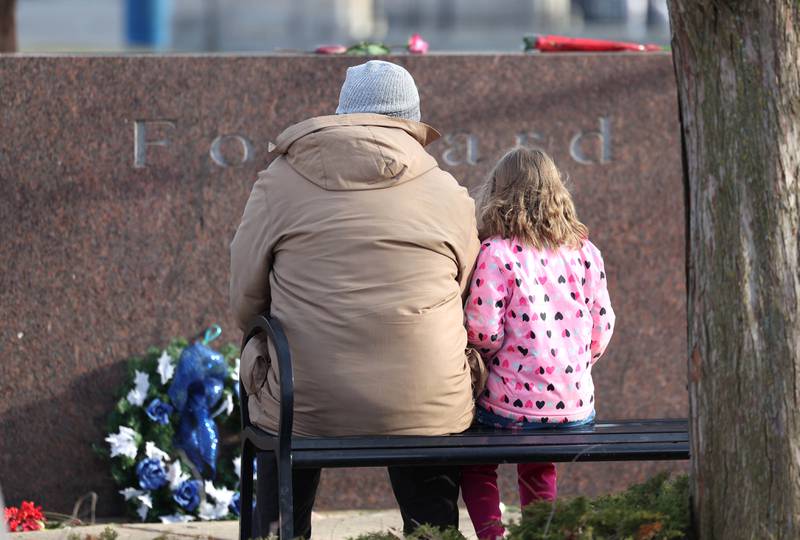 Attendees sit in front of one of the stones Wednesday, Feb. 14, 2024, during a ceremony in the Peaceful Reflection Garden near Cole Hall at Northern Illinois University honoring the victims of the 2008 shooting on campus in DeKalb. Wednesday marked 16 years since the deadly shooting took place at NIU which took the lives of five people.