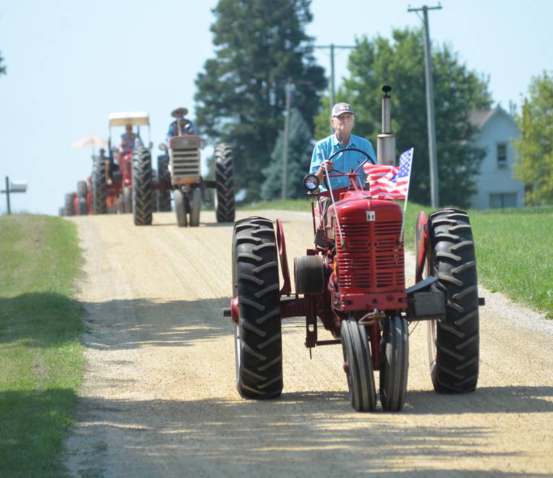 A participant in the Living History Antique Equipment Association's tractor drive heads down a hill on Hoosier Road, northeast of Franklin Grove, with other tractors and their drivers following. About 40 tractors took part in the ride that started at the association's show grounds in Franklin Grove and traveled to Oregon and back.