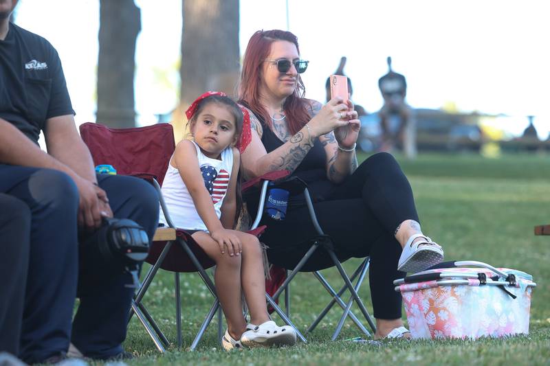 Mia Perez sits with her mother Amy Wallace while they listen to the live music at Dellwood Park in Lockport on Wednesday July 3, 2024.