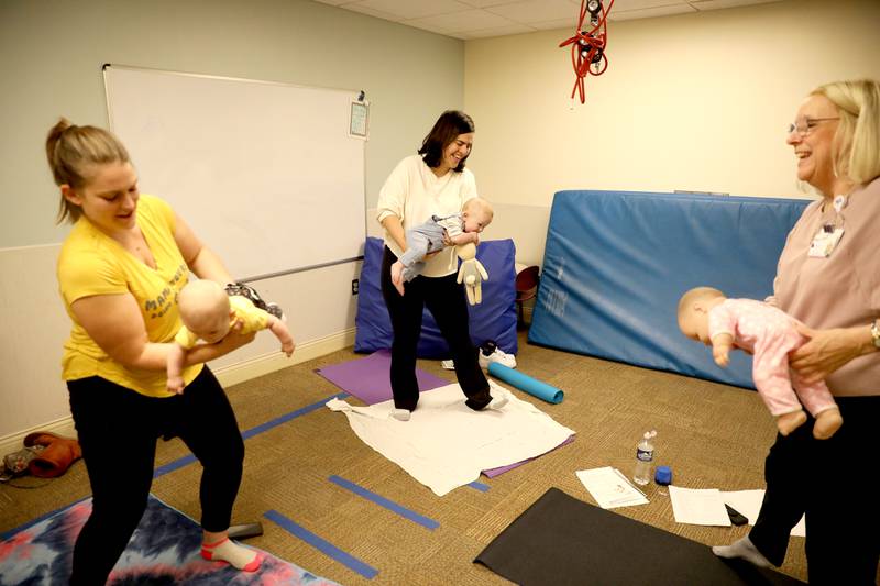 Patricia Ideran (far right), a pediatric occupational therapist and certified in baby yoga and massage for Northwestern Medicine, teaches a baby yoga class with (from left) Kristen Calvallo of Hanover Park and her daughter, Kalylah, 5 months, and Alicia Hollander of Wheaton and her son, Lucas, 5 months, at Northwestern Medicine Central DuPage Hospital in Winfield.