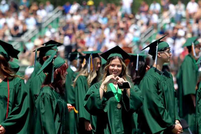 Juliana Almodovar signals to the crowd as she marches in for York High School’s graduation at the school in Elmhurst on Sunday.