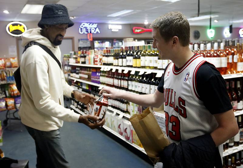 Tom Mason hand a bottle to retired Chicago Bulls star Scottie Pippen as Pippen signs  bottles of his Digits bourbon Thursday, Feb. 9, 2023, at The International House of Wine and Cheese, at 11302 Route 12, in Richmond.