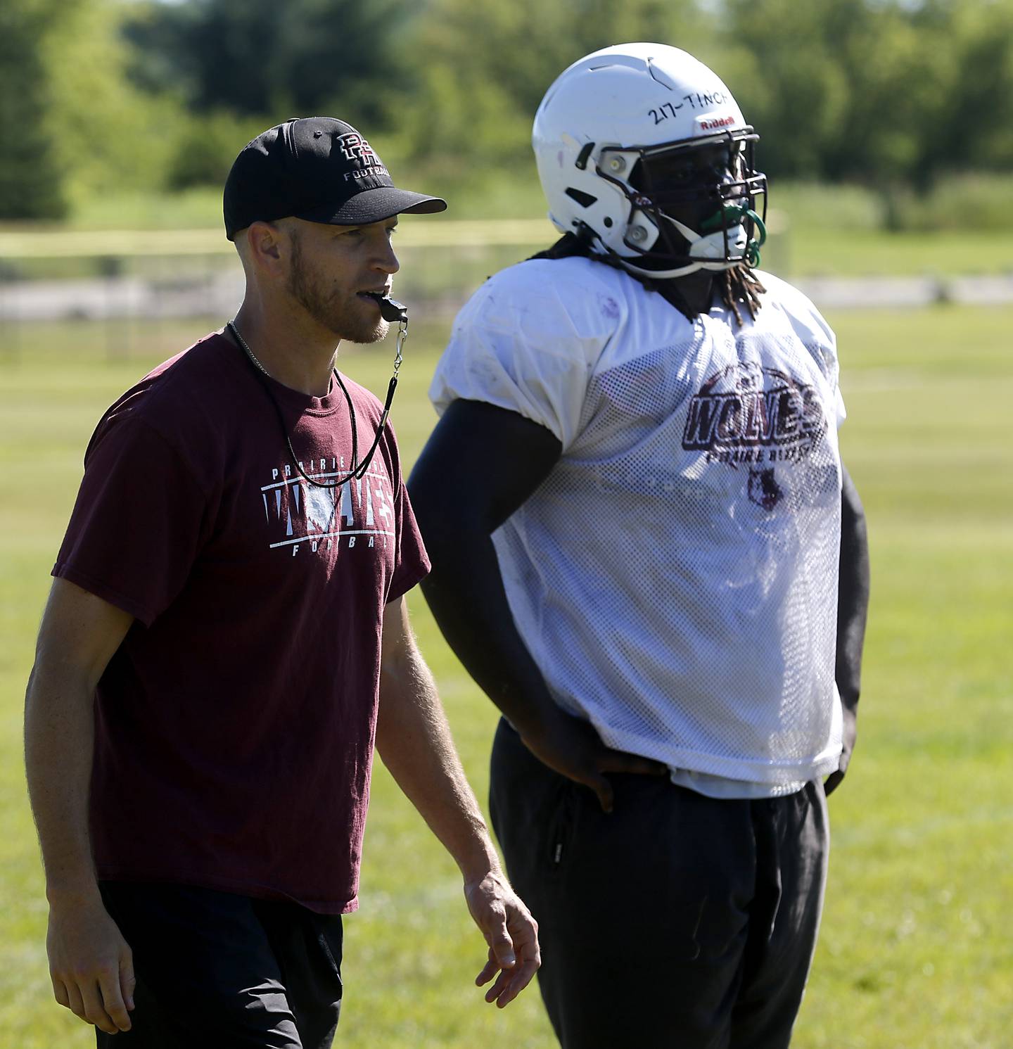 Prairie Ridge Head coach Michael Frericks watches a drill next to Gavin Tinch during football practice in July 2024 at Prairie Ridge High School .