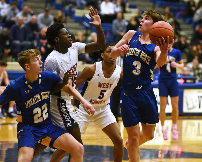 Wheaton North's Jack Speers (3) eyes the basket past teammate William Bonga (22) and West Aurora's Kewon Marshall (15) and Terrence Smith (5) during the boys basketball game on Monday, Jan. 15, 2024 in Geneva.