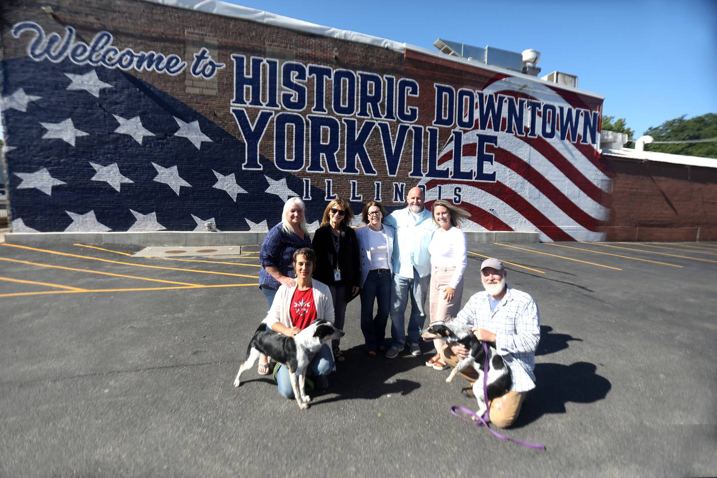 (Front row, left to right) Painter Rebekah Axtell, artist Joshua Schultz. (Back row from left) Jessica Frieders, Yorkville Economic Development Director Lynn Dubajic Kellogg, building owners Keri and Jason Pesola of Yorkville, PMG Creative Director Cami Lorentsen in front of Yorkville’s newest mural on the north side of Crusade Burger Bar at 209 S Bridge St. in downtown Yorkville.