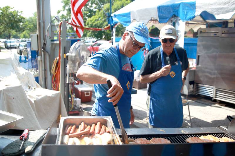 Tony Feldhaus (left) and Dick Bennett work the grill at the Knights of Columbus booth on opening day of Swedish Days in Geneva on Wednesday, June 19, 2024.
